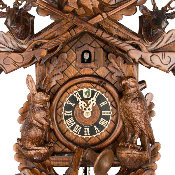  Cuckoo Clock - Carved 8-day hunting style cuckoo clock with large stag, mounted stag heads, rifles, fürst pless horn, rabbit, falcon, and game bag 52cm by Hönes - Cuckoo Collections
